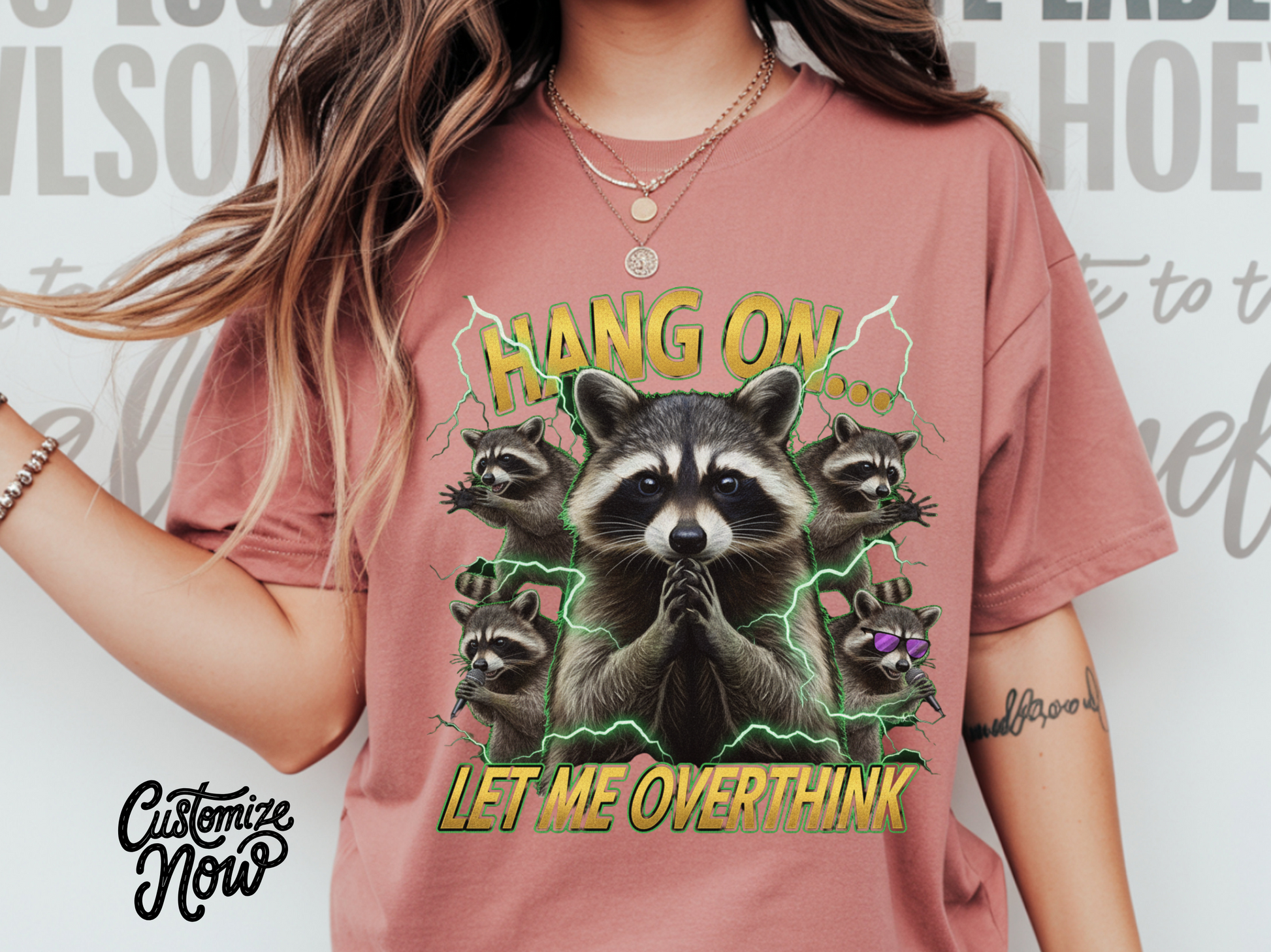 Person wearing a pink t-shirt with raccoon graphic and text 'Hang on, let me overthink' on a light gray background.